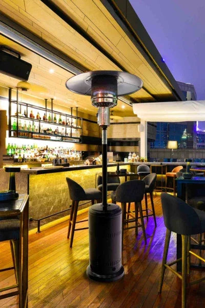 Estufa a gas para exteriores en terraza moderna con mesas y sillas de bar