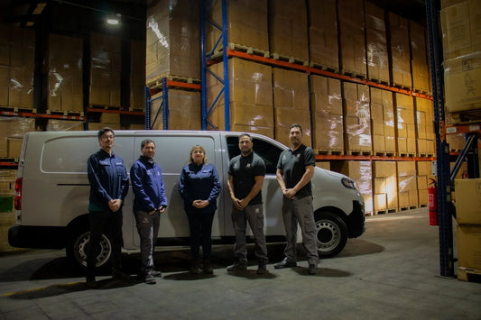Equipo de logística con uniforme junto a una van blanca en almacén con cajas apiladas